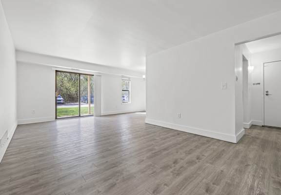 A spacious room with wooden flooring and white walls.