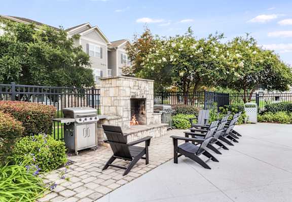 A patio with a fireplace, chairs, and a table.