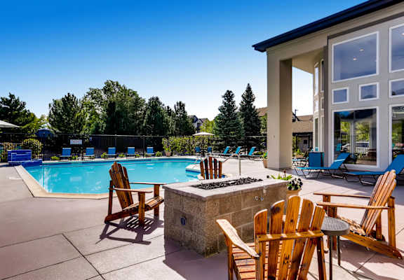A poolside area with chairs and a stone fireplace.