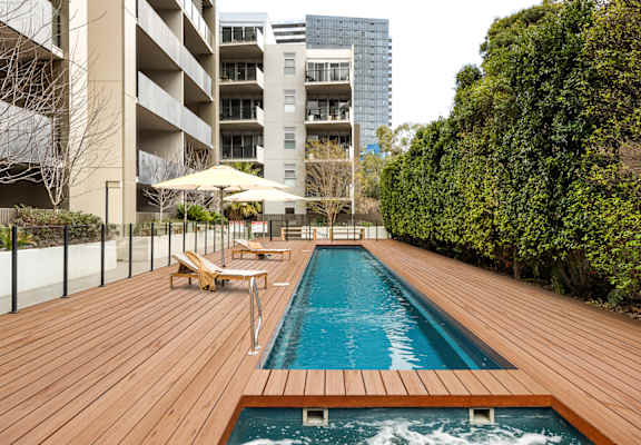 a swimming pool on a wooden deck next to an apartment building