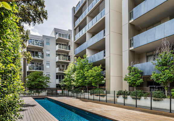 A modern apartment complex with a pool in the foreground.