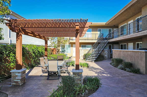 a patio with a table and chairs under a wooden pergola