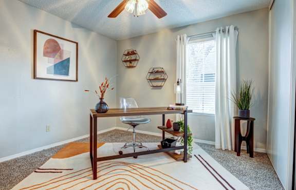 a desk with a chair in a room with a ceiling fan
