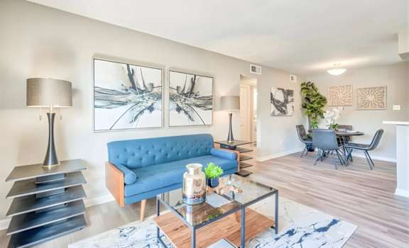 A blue sofa sits in a living room with a glass coffee table in front of it.