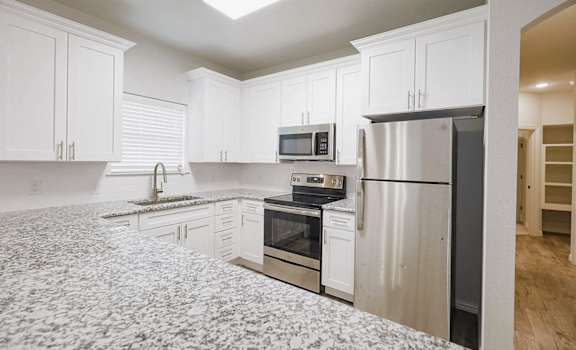 a kitchen with white cabinets and a black refrigerator