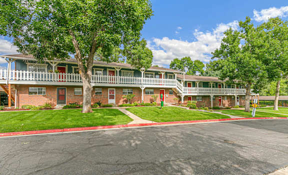 A large tree is in front of a two-story apartment building.