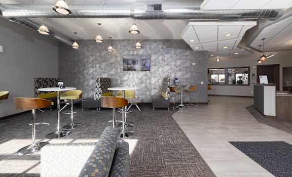 A modern office space with a grey stone wall and a long carpeted table.