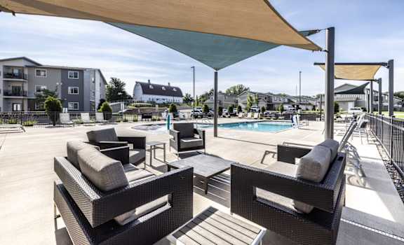 A patio with black wicker furniture and a pool in the background.