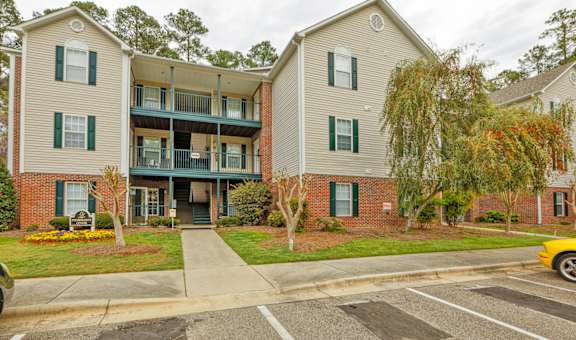 A two-story apartment building with a parking lot in front.