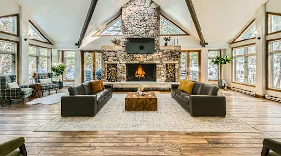 A large, open-concept living room with a stone fireplace and skylight.