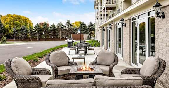 a patio with furniture and a fire pit in front of a house