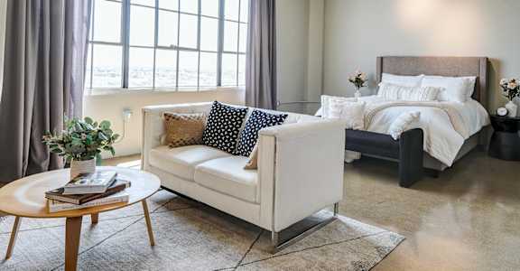 A bedroom with a large bed and a white couch.