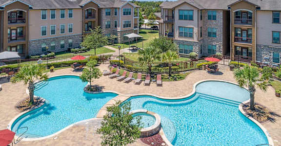 A large swimming pool surrounded by palm trees and lounge chairs.
