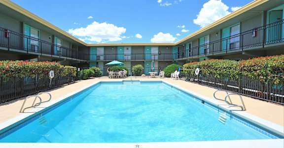 A swimming pool in a resort with sun loungers and umbrellas.