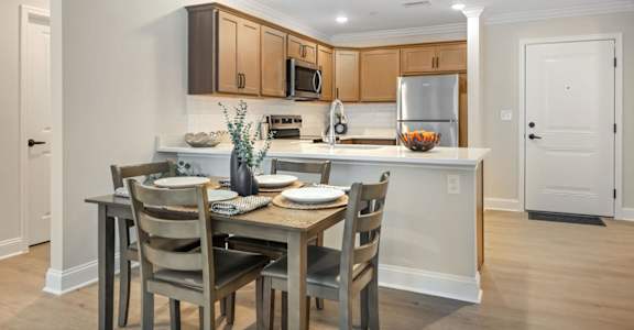 A kitchen with a table set for two with a bowl of fruit on the counter at The Promenade at Easton Apartments, Easton, 21601
