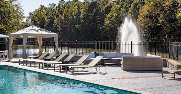 A pool with a fountain in the background and sun loungers in the foreground. at Inverness Cliffs, Birmingham, 35242