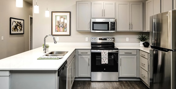 A modern kitchen with a white countertop and stainless steel appliances.