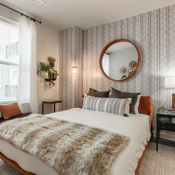 A bedroom with a large bed and a round mirror on the wall.