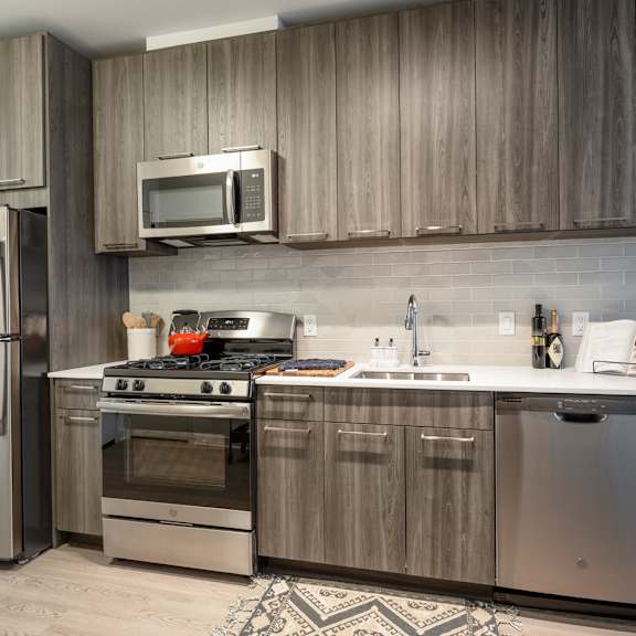A modern kitchen with a stainless steel refrigerator, oven, and microwave.