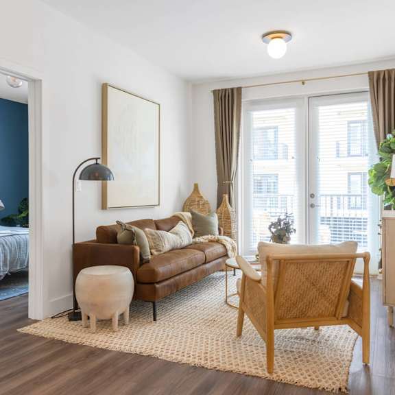 A living room with a grey bed and a brown couch.