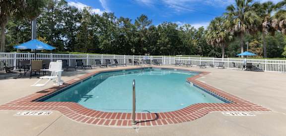 A pool surrounded by a fence with trees in the background.