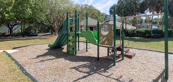 A playground with a green slide and a yellow and green play structure.