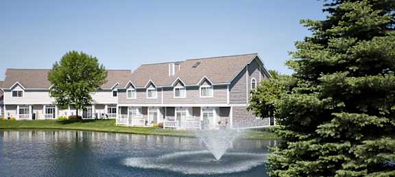 a fountain in the middle of a pond in front of a building