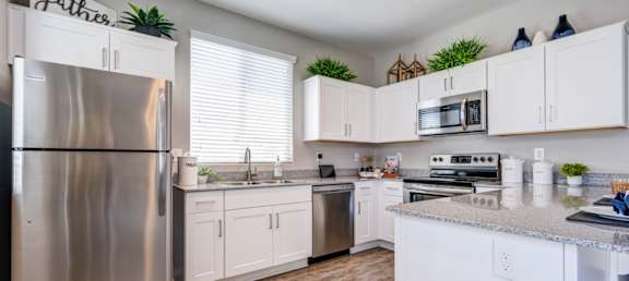 A kitchen with white cabinets and a stainless steel refrigerator.