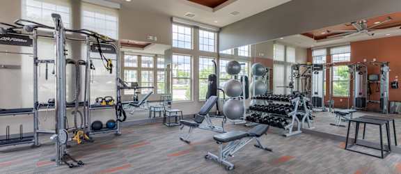 a gym with weights and cardio equipment and windows