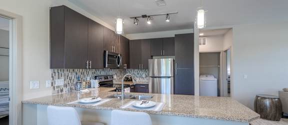 a kitchen with a granite counter top with white chairs