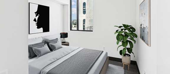 A bedroom with a bed, a potted plant, and pictures on the wall.