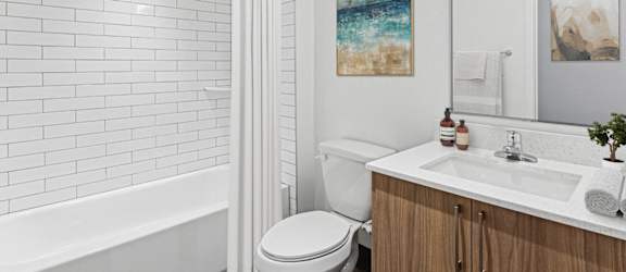 A white bathroom with a toilet, sink, and a painting on the wall.