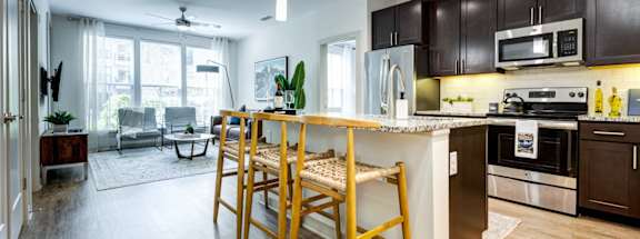 an open kitchen and living room with a bar and wooden stools