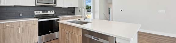 A modern kitchen with a white countertop and wooden cabinets.