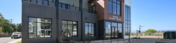 A modern building with a glass facade and a brown roof.