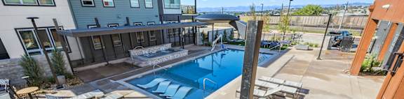 A pool area with sun loungers and a building in the background.