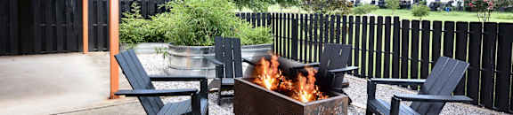 a patio with a fire pit and chairs and a black fence at Capital Flats & Magnolia Square Apartments, North Carolina, 27601