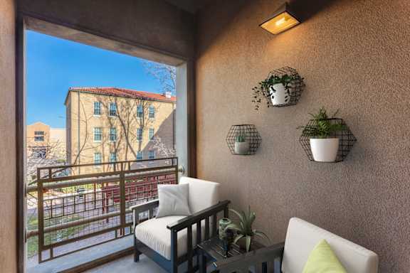 A balcony with a chair and a table with a potted plant on it.