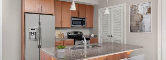 A kitchen with a refrigerator, microwave, oven, sink, and bar stools.