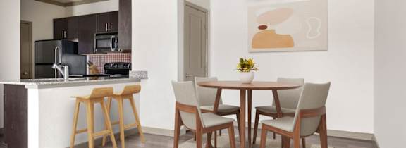 A kitchen with a dining table and chairs.