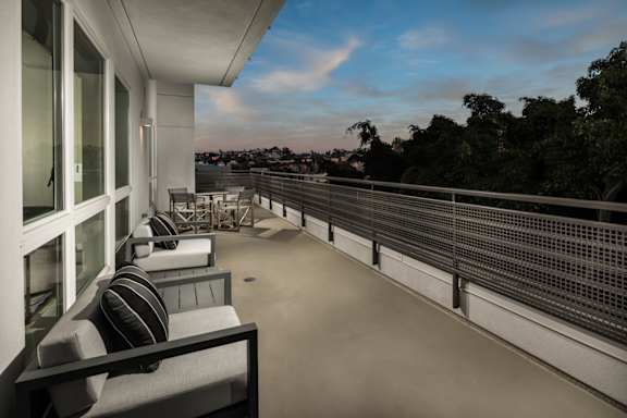 A balcony with a metal railing and a couch with a striped pillow.