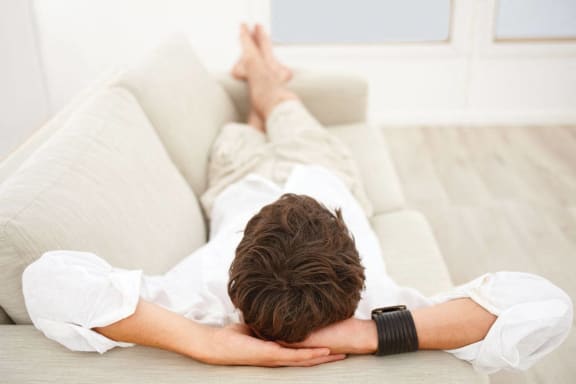 a man laying on a couch with his head on his hands