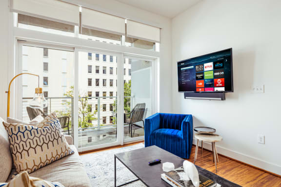 a living room with a couch and a chair and a tv on the wall at 20 Midtown, Birmingham, Alabama