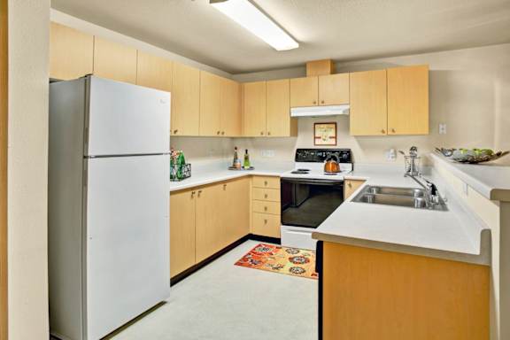 A kitchen with a white refrigerator and wooden cabinets.