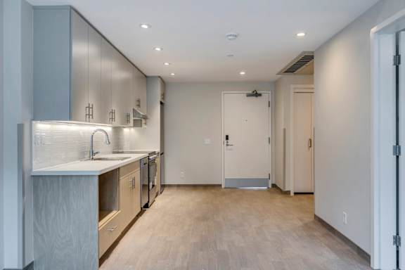 a kitchen with a sink and a counter and a door to a hallway