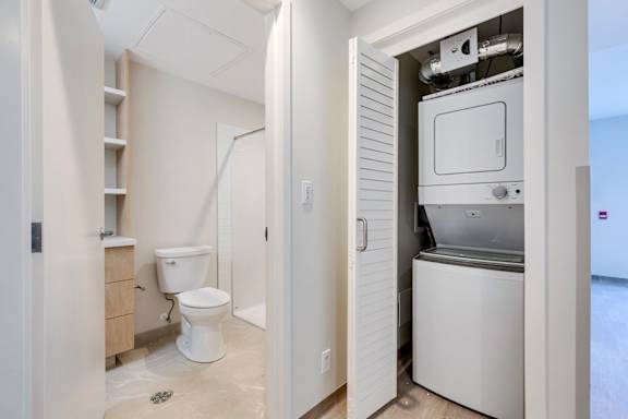 a laundry room with a toilet and a washer and dryer in a bathroom