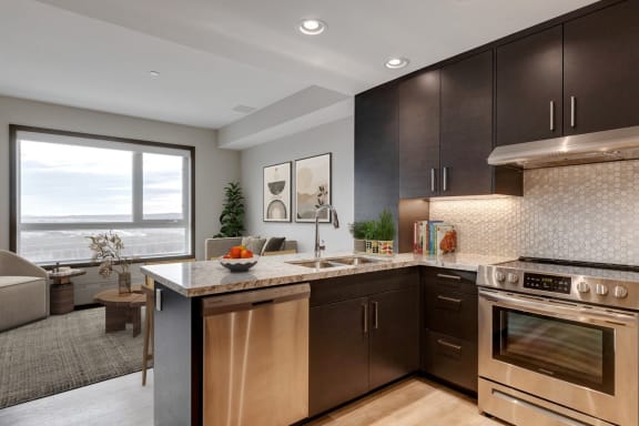an apartment kitchen with stainless steel appliances and wooden cabinets