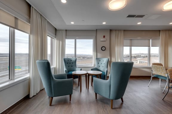 a waiting room with blue chairs and a table and windows