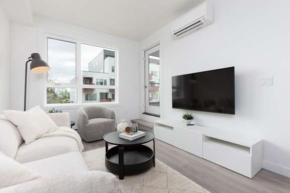 A living room with a grey couch, a glass table, and a framed picture on the wall.