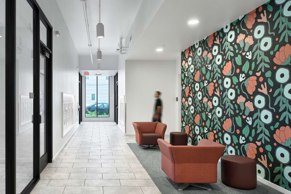 an image of a corridor with a large mural of flowers on the left and a person walking